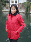 Red quilted jacket on model with dark collar, full zip, diamond stitching and long sleeves.