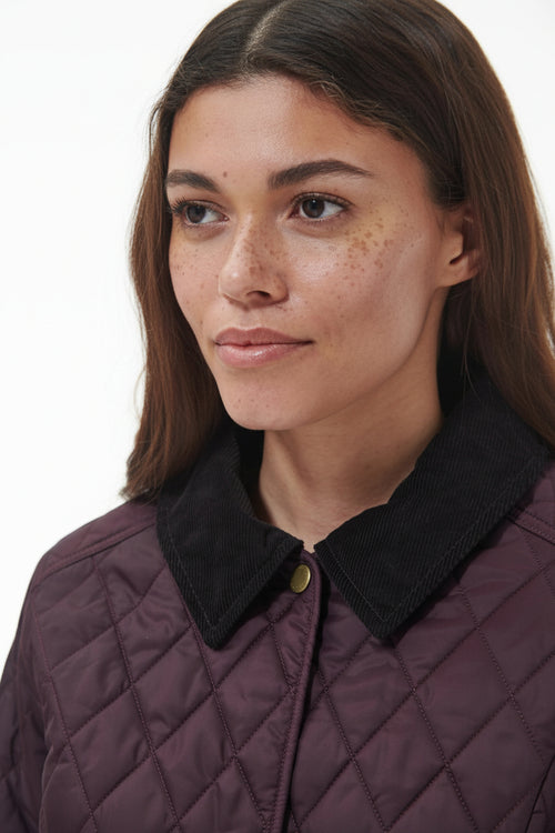 Women’s quilted jacket with dark plum fabric, black collar, and gold button
