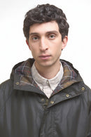 Dark olive wax parka collar with hood and tan-and-brown plaid inner lining.