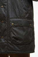 Dark olive wax parka front pocket with Barbour label and buttoned flap.