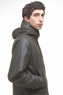 Dark olive wax parka jacket side view with high collar and stitched shoulder.