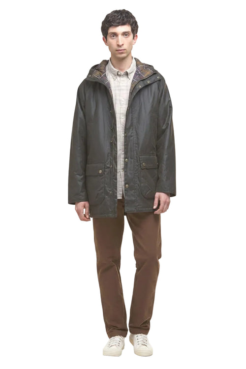 Dark olive hooded wax parka jacket with plaid inner collar, worn over tan shirt.