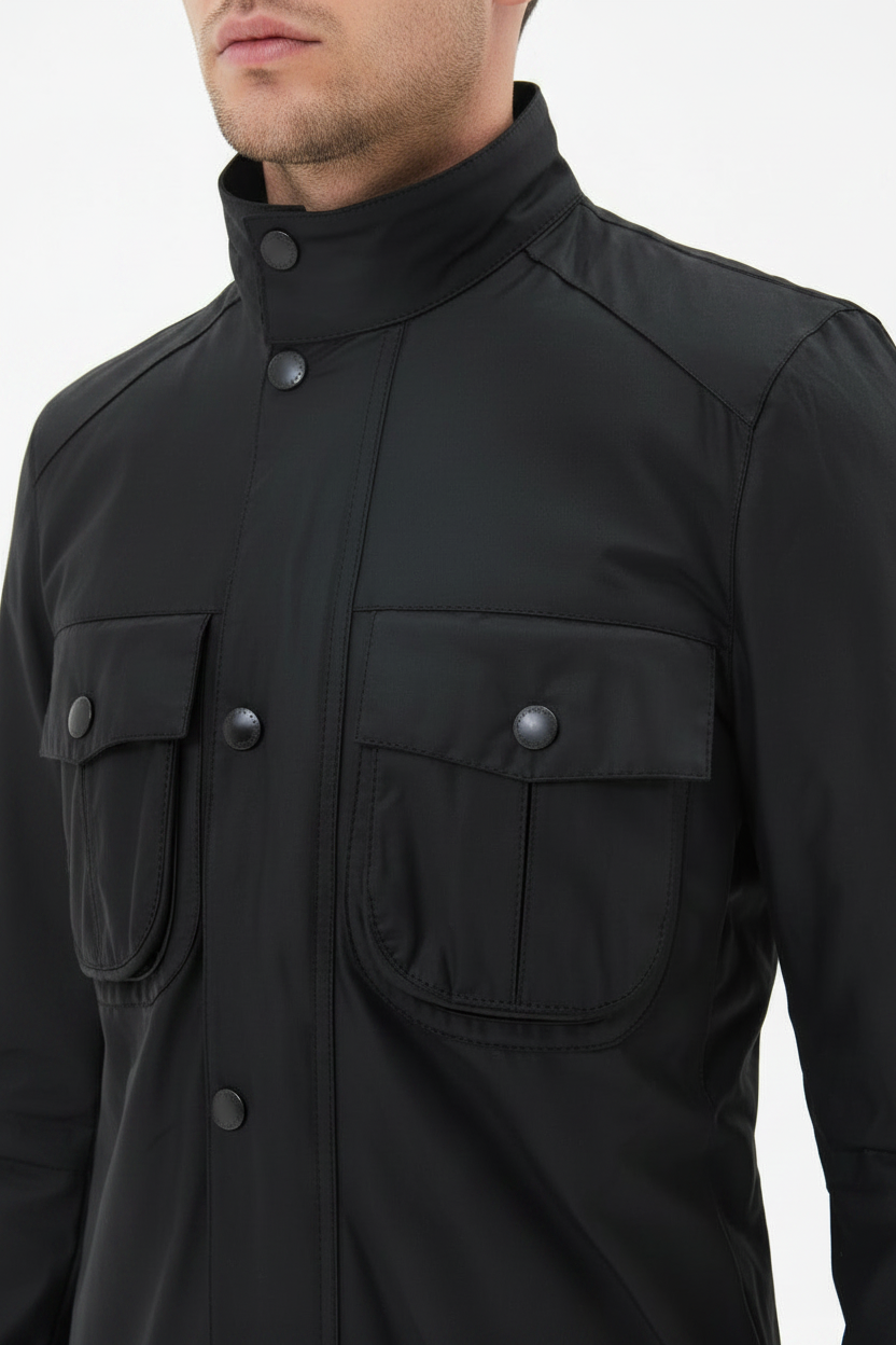 Men's black wax jacket close-up with stand collar and buttoned flap chest pocket.