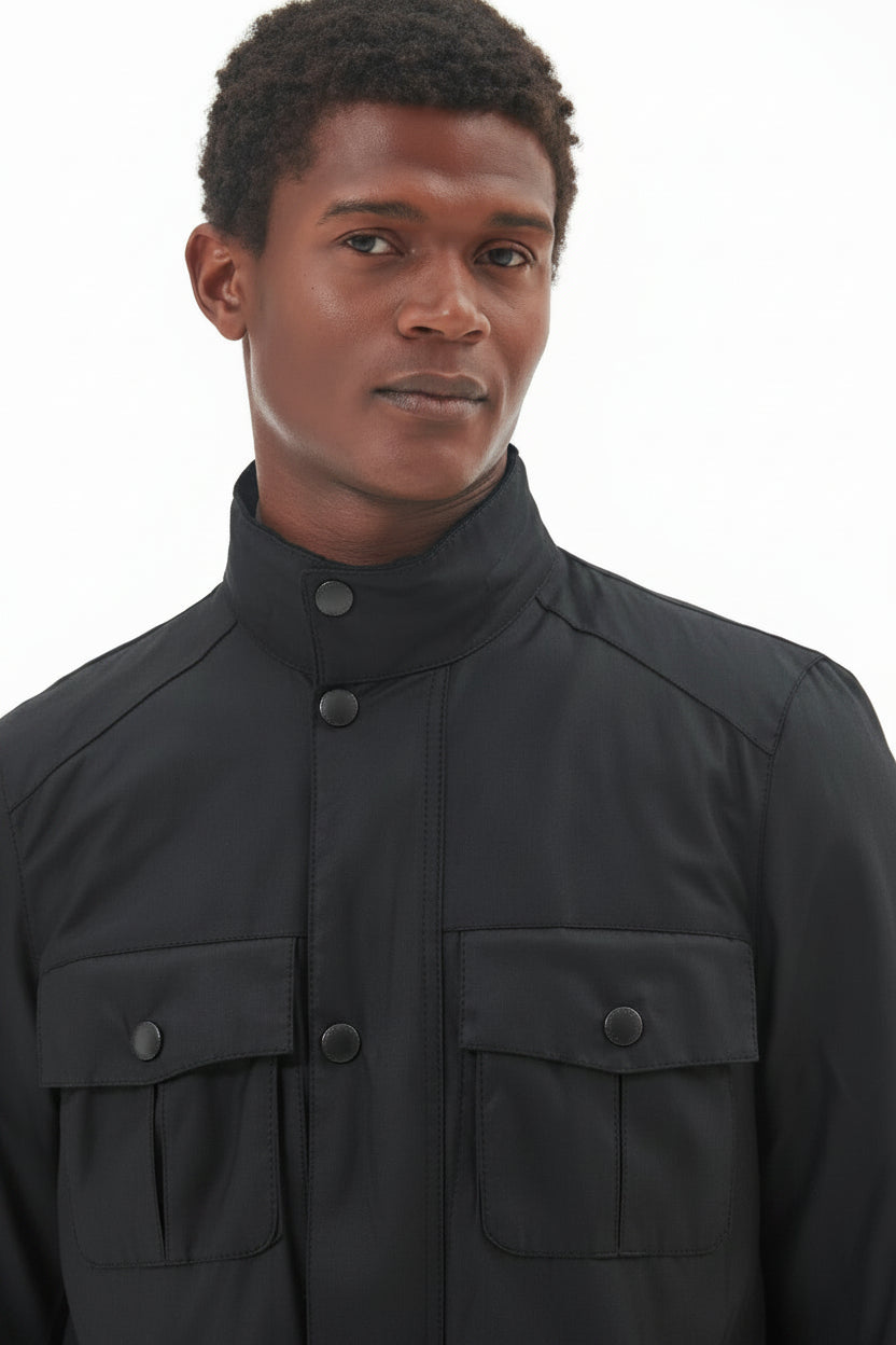Men's black wax jacket close-up with stand collar and two snap buttons at throat.