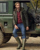 Men's dark green waxed jacket with hood and front zip, worn over a red plaid shirt.