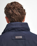 Back of navy waterproof jacket with stitched logo patch on the hood.