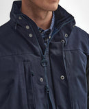 Navy waterproof jacket close-up with zip front, hood drawcord, and button placket.