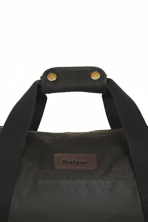 Dark olive duffle bag close-up: webbing handles and Barbour logo patch on front