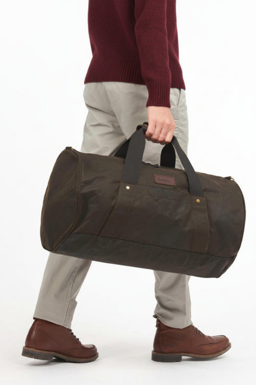 Dark olive duffle bag carried by a shoulder strap; zip top with metal snap details
