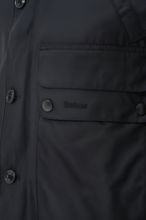 Barbour wax parka chest pocket and snap buttons with small logo patch on dark fabric