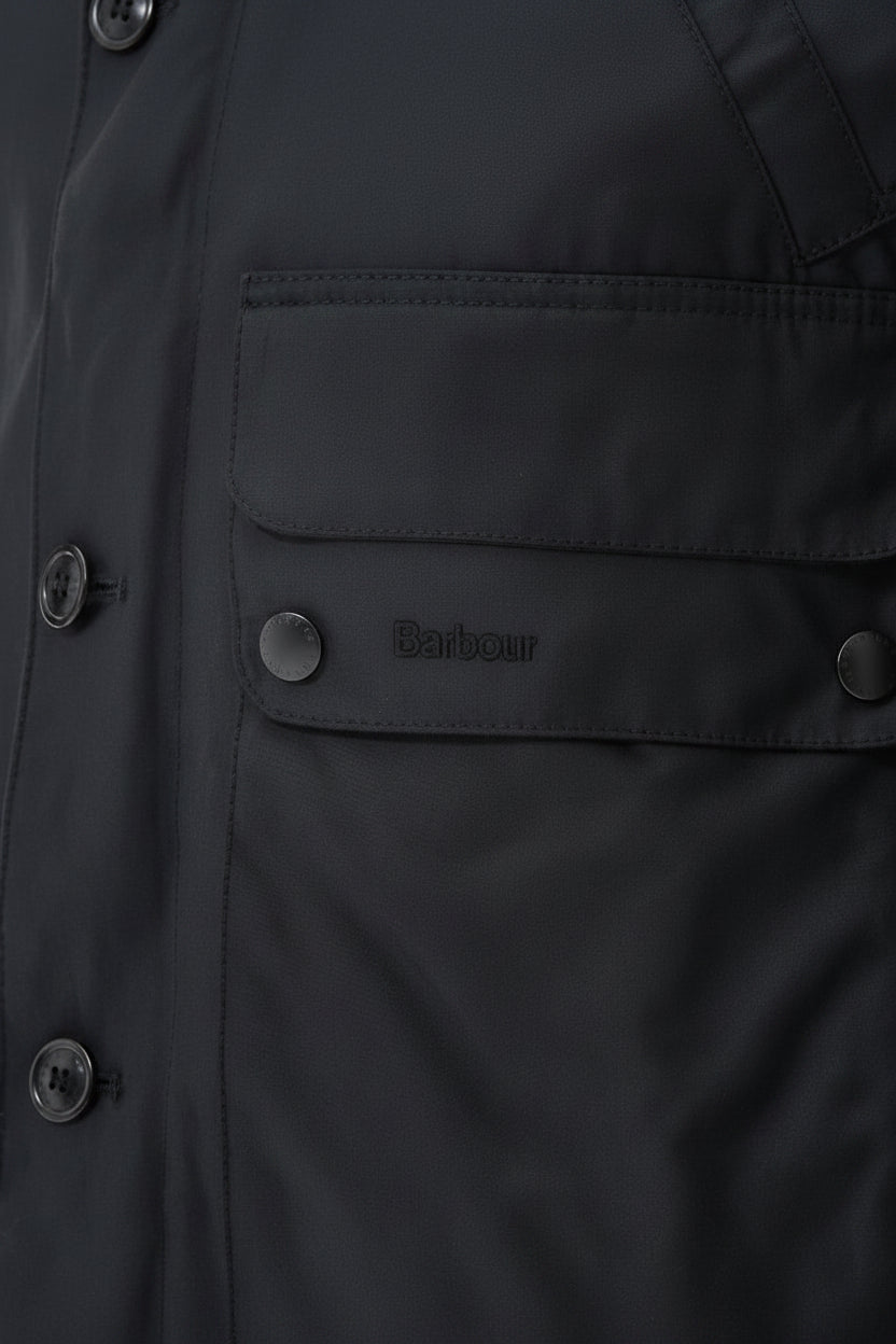 Barbour wax parka chest pocket and snap buttons with small logo patch on dark fabric