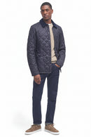 Men's navy quilted jacket with button front, styled with jeans and tan shoes