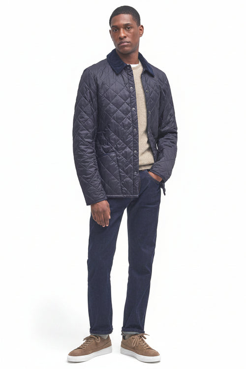 Men's navy quilted jacket with button front, styled with jeans and tan shoes