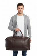 A dark brown leather duffel bag with dual top handles, a front zippered pocket, and brass-tone hardware, shown against a plain white background.