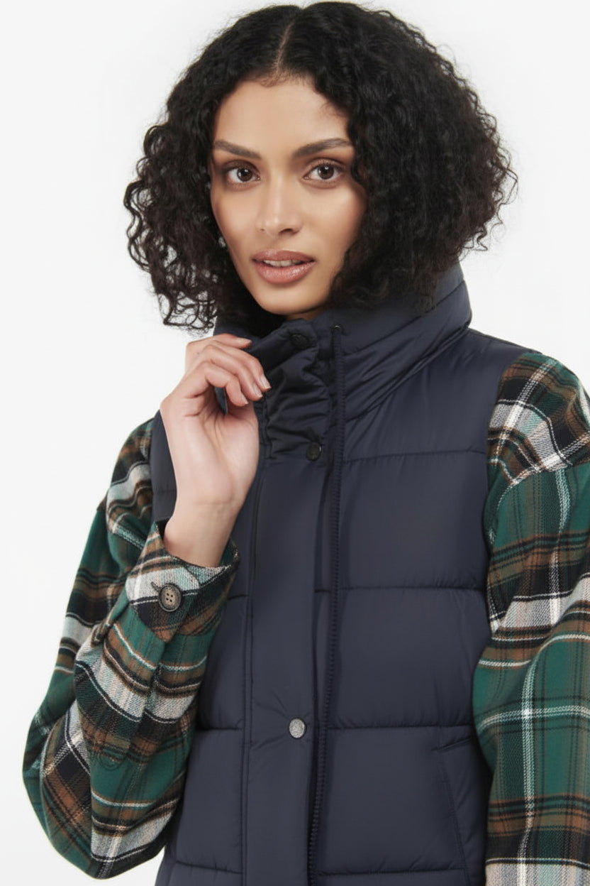 Navy quilted hooded gilet with button front, worn over plaid sleeves