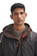 Men's dark wax parka with hood, snap placket, and tan leather-style trim.