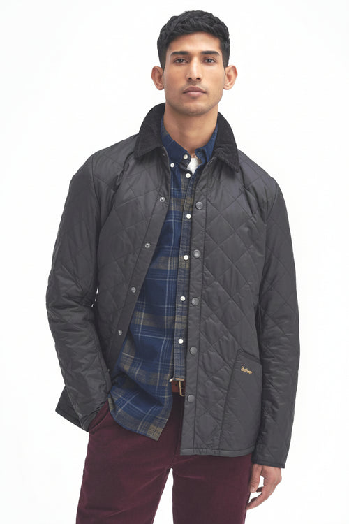 Men's black quilted jacket worn with blue plaid shirt, Barbour logo on chest