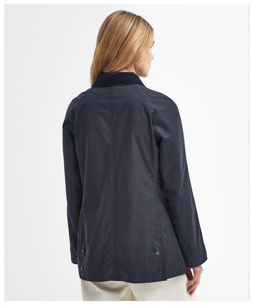 Navy women's wax Beadnell jacket with snap front and side buttoned hem tabs