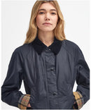 Navy wax jacket with cord collar, button placket, and plaid cuffs showing at wrists