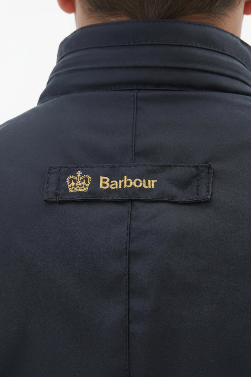 Men's navy wax jacket back yoke with Barbour brand patch near the collar