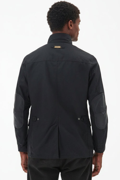 Men's black wax jacket back view with quilted shoulder and patch pocket