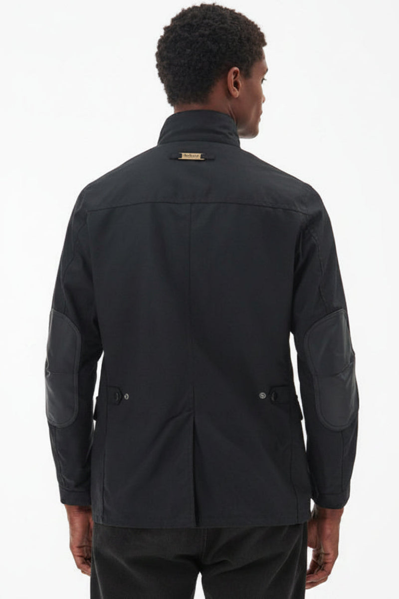 Men's black wax jacket back view with quilted shoulder and patch pocket