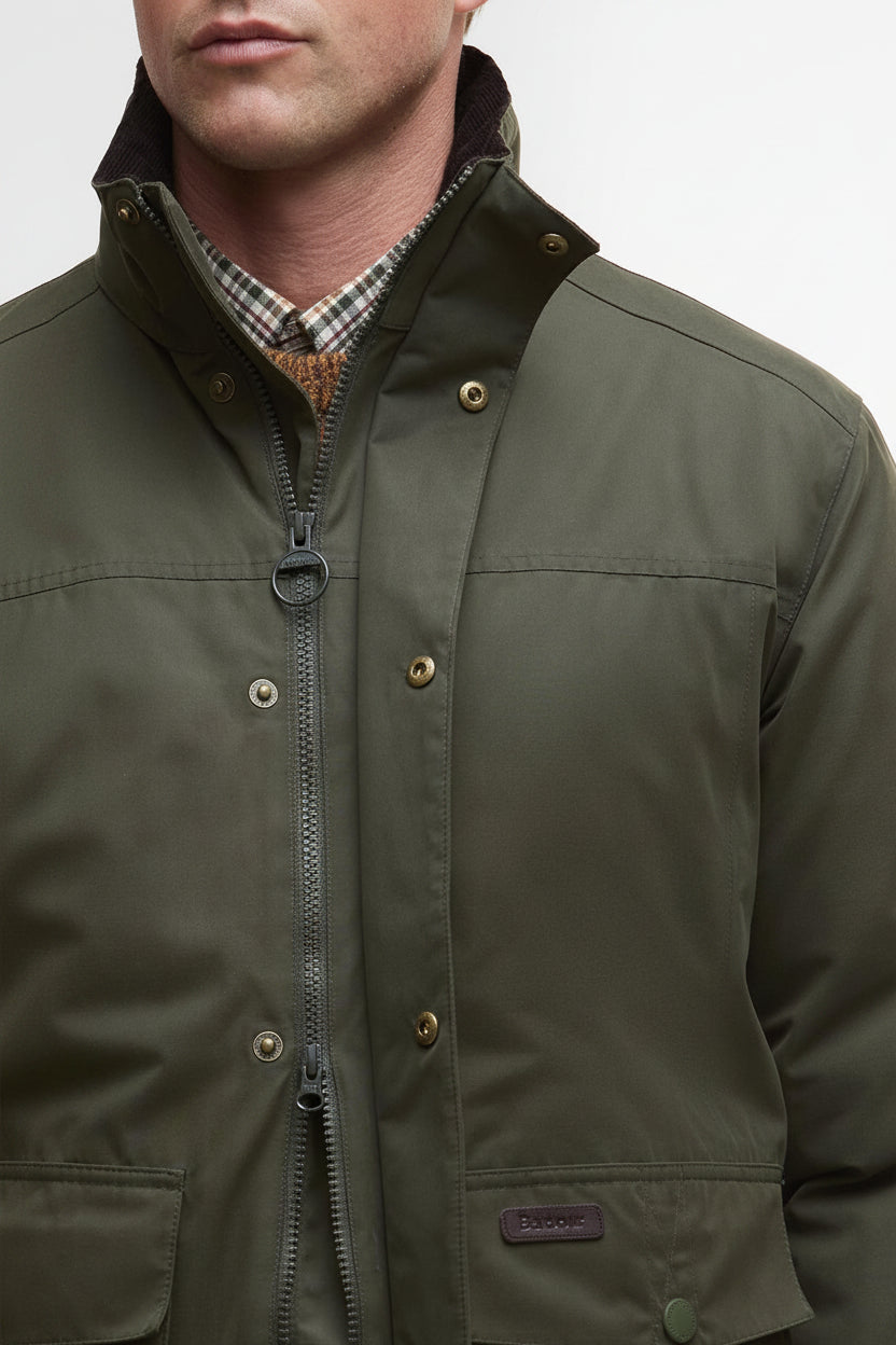 Olive waterproof jacket front close-up with zip, snap buttons, and chest badge