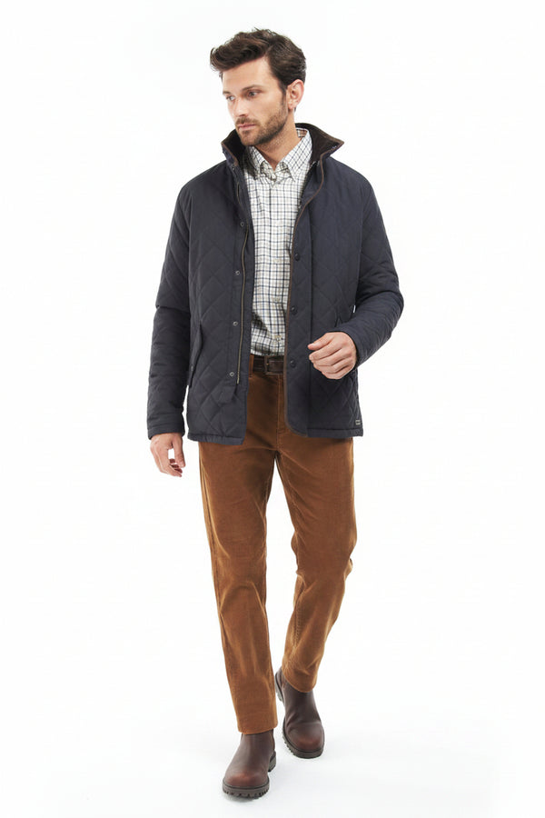 Mens quilted jacket worn over a check shirt with brown trousers