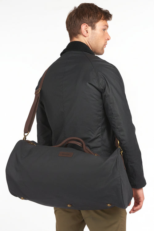 Dark navy wax holdall bag with long shoulder strap and brass zip pull