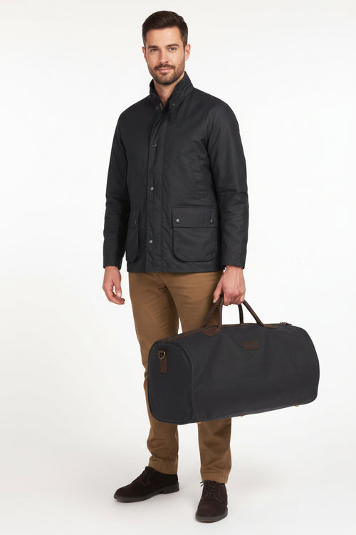 Navy wax holdall bag with leather straps, zip closure, and carry handles