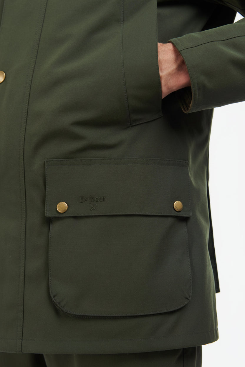 Men's sage green jacket detail: flap chest pocket with brass-tone snap buttons.