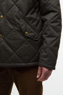 Dark olive quilted jacket sleeve with snap welt pocket and textured fabric close-up