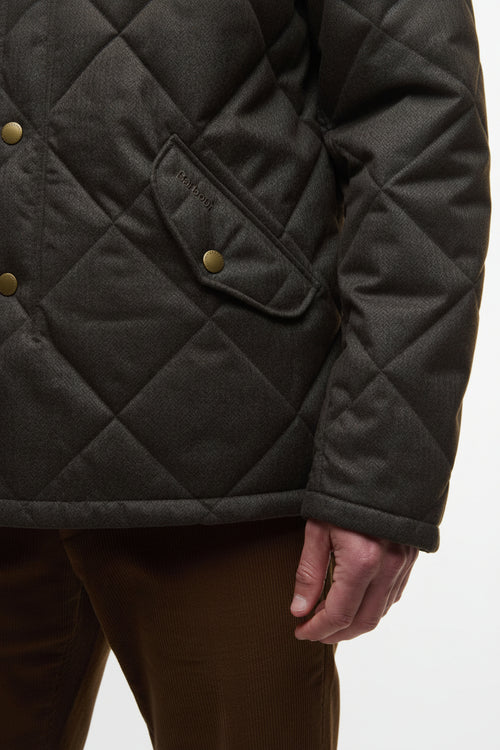 Dark olive quilted jacket sleeve with snap welt pocket and textured fabric close-up