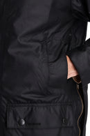 Black wax jacket pocket with snap closure and Barbour logo patch at hem
