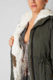 Women's green parka hood with white fur trim and visible front zip placket