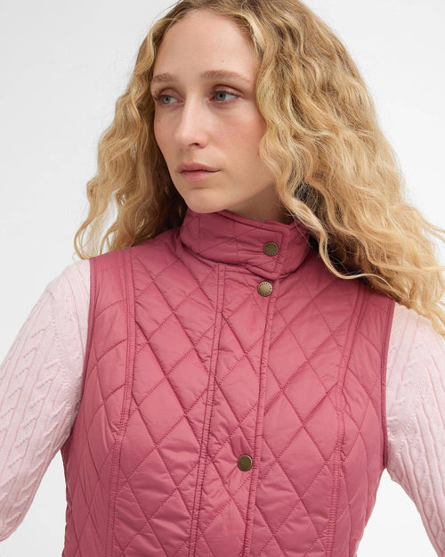 Wildberry pink quilted gilet close-up: stand collar, green snap buttons, diamond stitch