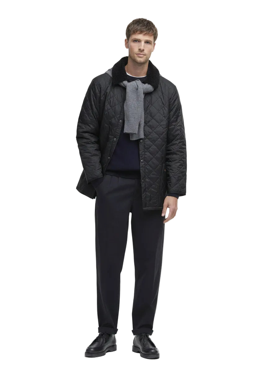 Barbour men's black quilted jacket worn over a crewneck and trousers