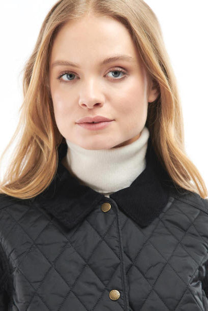 Black quilted women’s jacket with gold-tone buttons and stand collar, face-level close-up