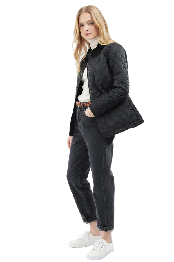 Black quilted women’s jacket with button front, side profile view with jeans styling