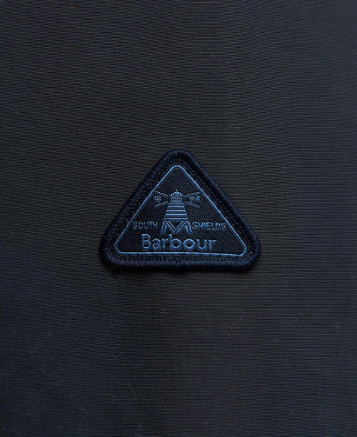 Embroidered Barbour triangle logo badge on dark navy fabric