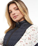 Navy quilted gilet with high neck and gold front zip, worn over floral blouse