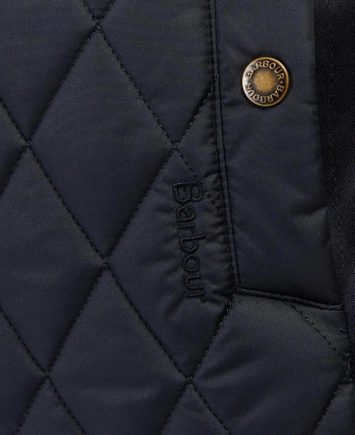 Navy quilted gilet close-up with Barbour round badge and branded zipper pull