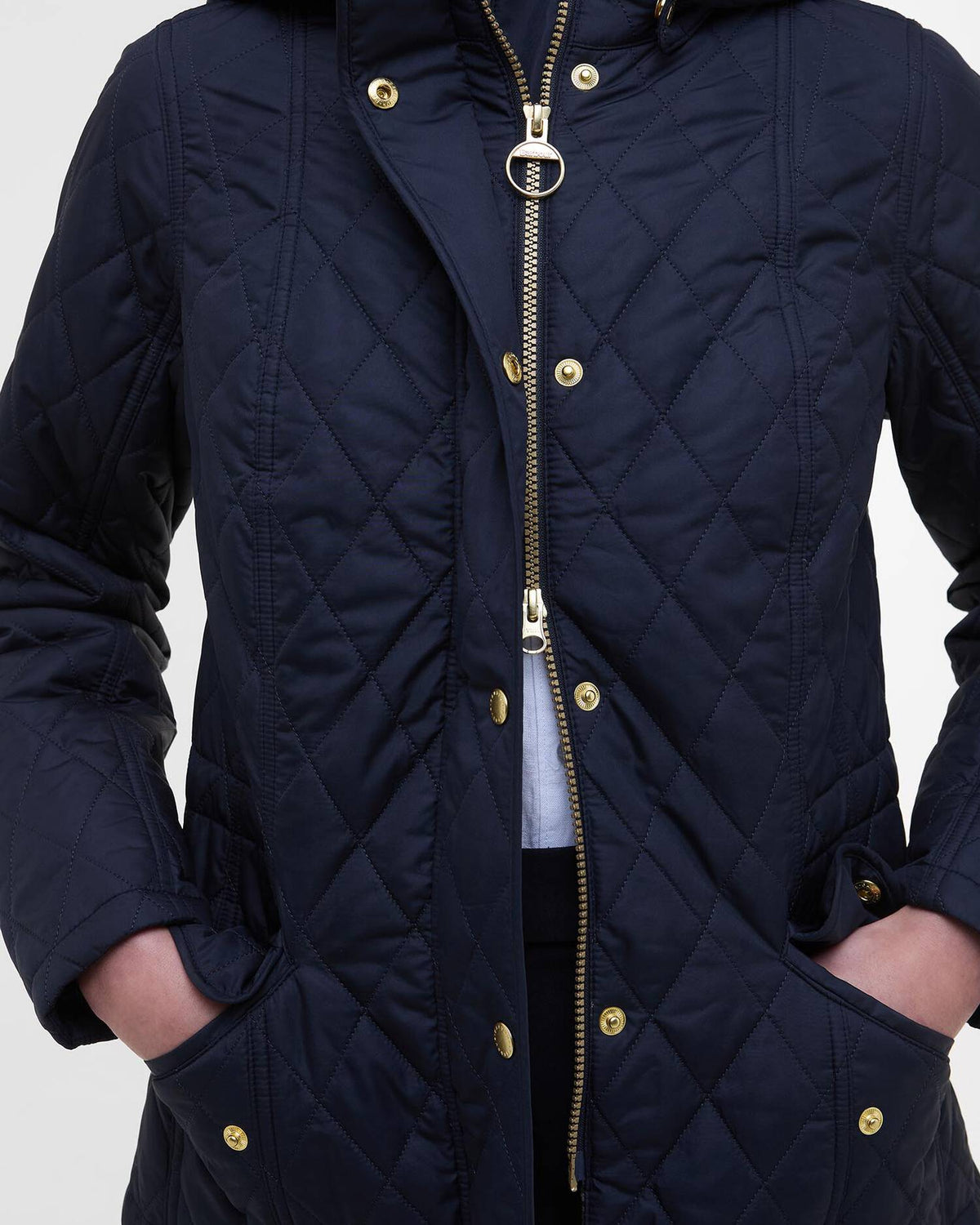 Navy quilted jacket front close-up with gold zip pull, gold buttons, hood toggle ring