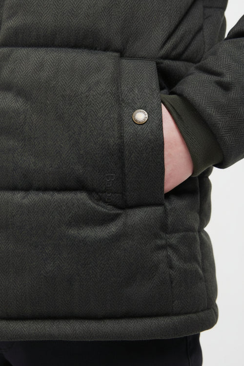 Dark quilted jacket cuff with metal snap and stitched panel detail.