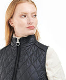 Black quilted gilet with full zip and stand collar; knit sleeve detail at shoulder