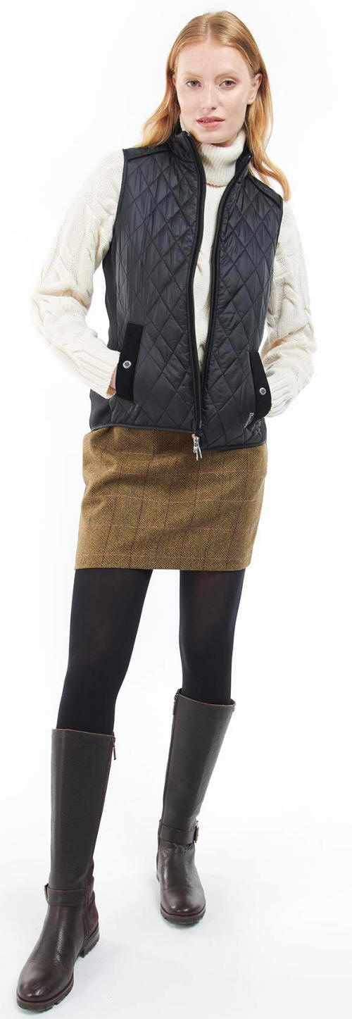 Black quilted gilet vest worn over knit sleeves with front zip and pockets