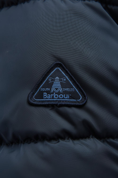 Barbour logo patch on dark navy quilted jacket, triangle emblem on chest