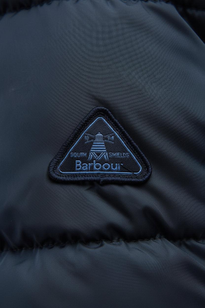Barbour logo patch on dark navy quilted jacket, triangle emblem on chest