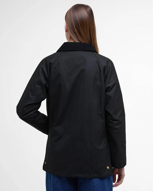 Black women’s wax jacket with stand collar and buttoned back yoke; rear view