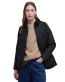 Black women’s wax jacket with stand collar, gold-tone buttons, and side flap pockets